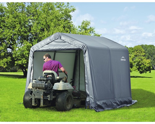 Tuinscene met een opbergtent voor een zitmaaier en een zitmaaier