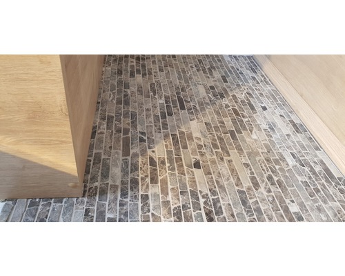 Detailopname van een vloer met mozaïektegels en een houten kast