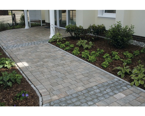 Geplaveid pad naar een huis met beplante borders