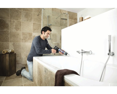 Man dicht bad af met een kitpistool in een badkamer