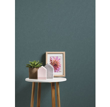 Decoratieve scène met potplant, huisfiguren en ingelijste foto op een ronde tafel tegen een gestreepte achtergrond