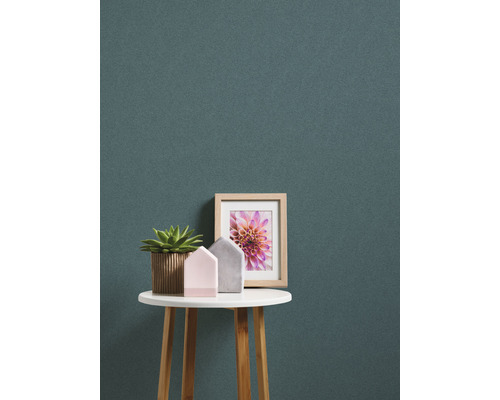 Decoratieve scène met potplant, huisfiguren en ingelijste foto op een ronde tafel tegen een gestreepte achtergrond