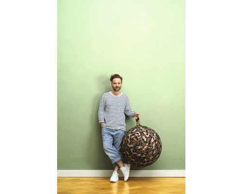 Man leunt tegen een muur en houdt een ronde zitzak met camouflagepatroon vast