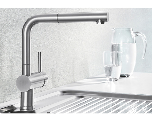 Keukenkraan van roestvrij staal naast gootsteen en waterkan