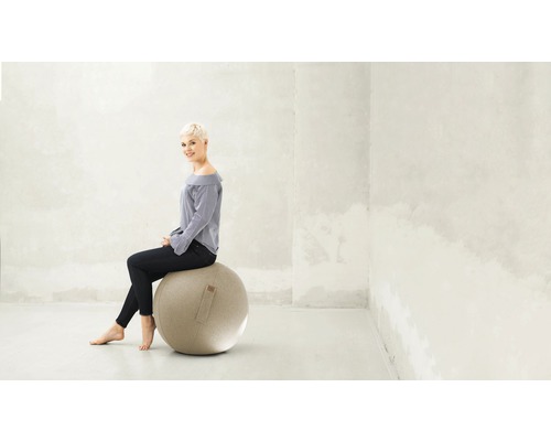 Vrouw zit op een gymbal in een heldere ruimte.
