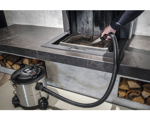 Iemand maakt een open haard schoon met een aszuiger.