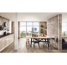 Lichte woonkamer met eettafel, stoelen, kitchenette en bakstenen muur