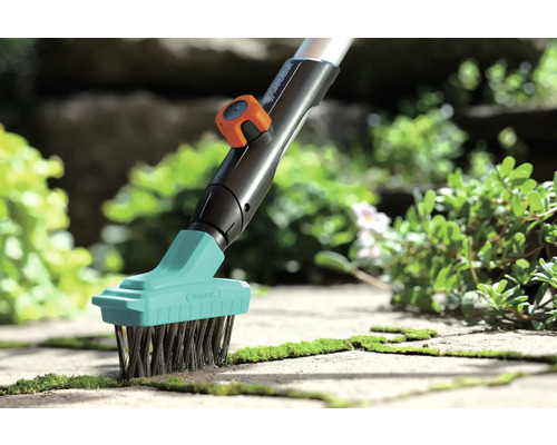 Gardena voegenborstel met stalen borstelharen in gebruik voor het verwijderen van mos op stenen platen