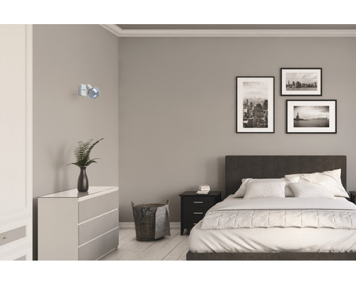 Slaapkamer met bed, commode, nachtkastje, wandlamp en ingelijste foto's