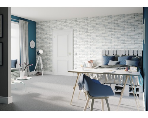 Lichte slaapkamer met bed, bureau en bakstenen muur