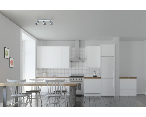 Lichte ruimte met kitchenette, eettafel en plafondlamp met drie spots.