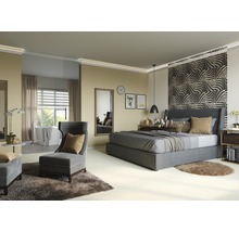 Slaapkamer met bed, fauteuil en bad op de achtergrond