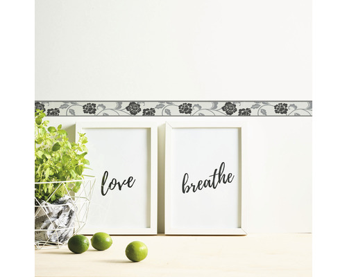 Wandbordüre met bloemenmotief boven twee ingelijste foto''s met de woorden Love and Breathe.