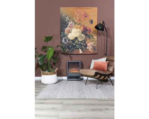 Woonkamer met vloerkleed, fauteuil, kamerplant, elektrische haard, staande lamp en muurdecoratie