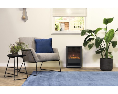 Woonkamer met fauteuil, kussen, tafel, kamerplanten, elektrische haard en vloerkleed