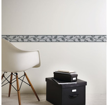 Wandborder met bladerpatroon in kamer met stoel en opbergdozen