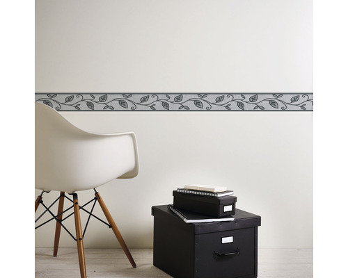 Wandborder met bladerpatroon in kamer met stoel en opbergdozen