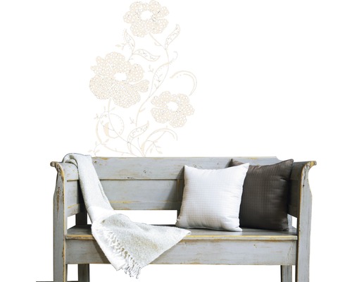 Decoratieve bloemenmuursticker boven een houten bank met kussens en een deken