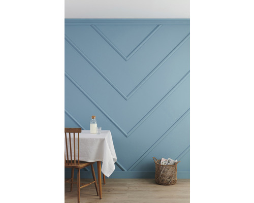 Interieur met blauw geschilderde muur met sierlijsten, tafel met wit laken, stoel en mand