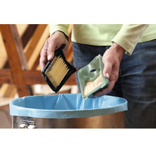 Persoon leegt stofzuigerfilter boven een vuilnisbak