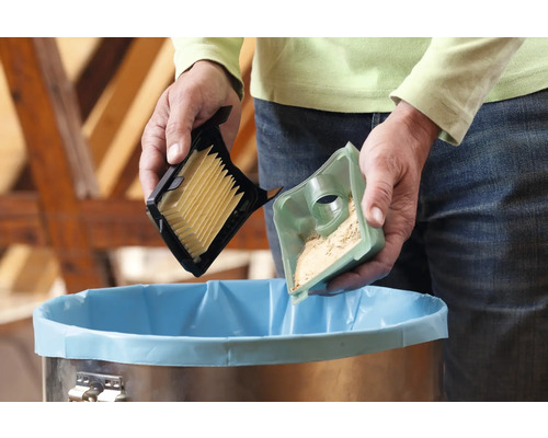 Persoon leegt stofzuigerfilter boven een vuilnisbak