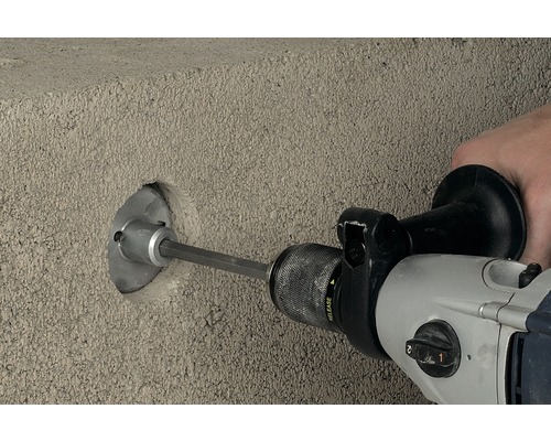 Een boormachine boort een gat in een betonnen muur.