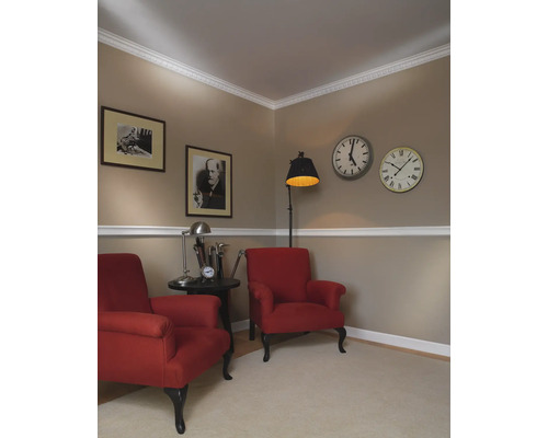 Twee rode fauteuils met bijzettafel, vloerlamp en wandklokken in een woonkamer
