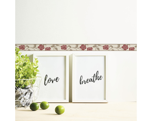 Decoratieve rand met bloemmotief op een muur boven twee ingelijste foto''s