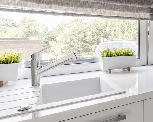 Keukenspoelbak met kraan op een aanrecht voor een raam