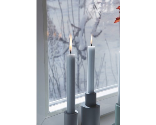Brandende stompkaarsen op kandelaars op vensterbank