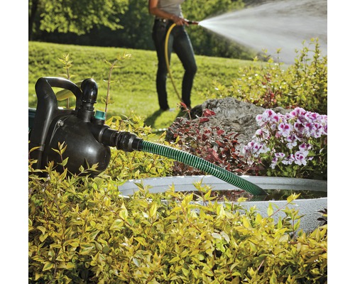 Tuin met tuinpomp, slang en een persoon die water geeft met een tuinslang