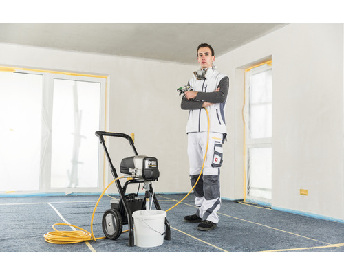 Man met verfspuitapparaat in een kamer.