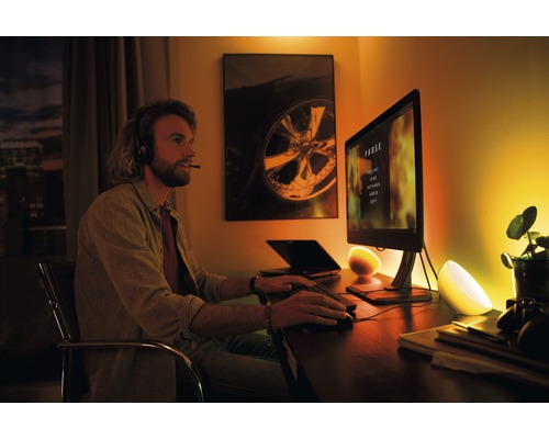 Scène van een man met headset voor een computer, verlicht door twee tafellampen