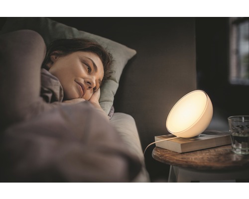 Een vrouw ligt in bed naast een bedlamp.