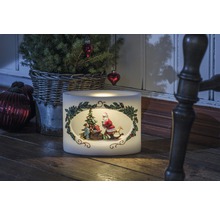 Decoratieve kerstkaars met kerstmanmotief naast kleine kerstboom