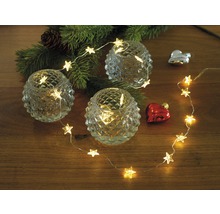 Decoratieve opstelling met theelichthouders, sterrenlichtsnoer en kerstversiering op een tafel.