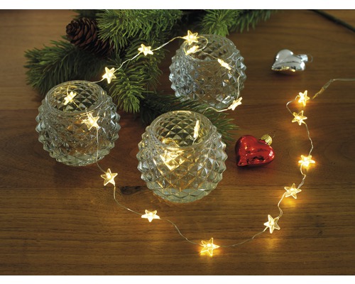 KONSTSMIDE Kerstverlichting LED sterren lichtsnoer 40 lampjes warmwit 2,1 m Decoratieve opstelling met theelichthouders, sterrenlichtsnoer en kerstversiering op een tafel.