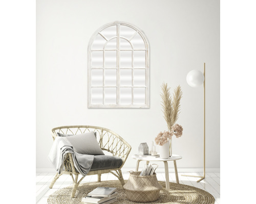 Woonkamer met spiegel in boogvenstervorm, rotan stoel, bijzettafel en vloerlamp
