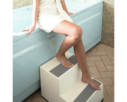 Vrouw met handdoek stapt met trap in bad