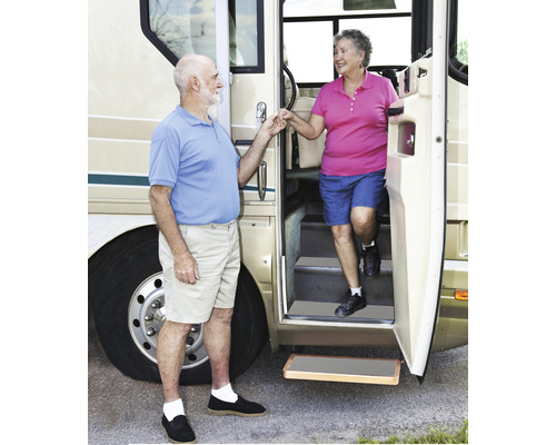 Een echtpaar stapt uit een camper met een uitschuifbare opstap.