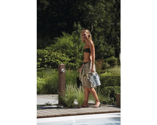 Vrouw met gieter in een tuin met kraan