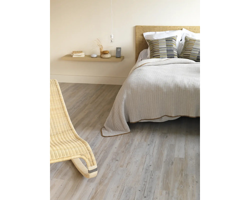 Slaapkamer met bed, nachtkastje en rotan stoel op houten vloer