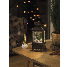 Decoratieve scène met een sneeuwbollantaarn, een kabouterfiguur en een kamerplant op een tafel