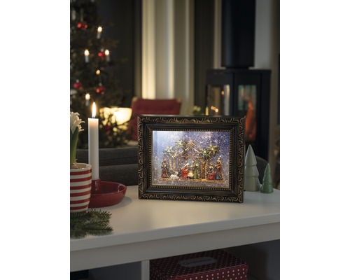 Decoratieve kerststal in fotolijst met kerstscène op een tafel
