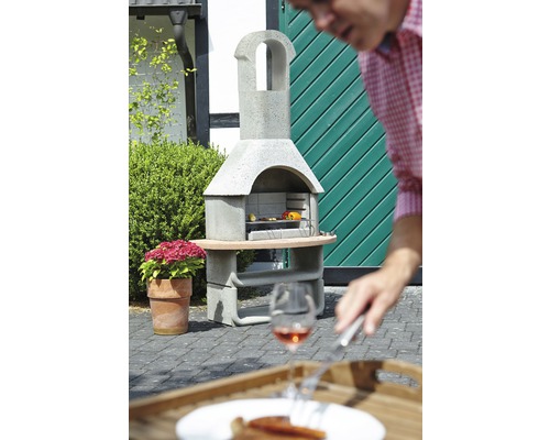 Gemetselde barbecue met eten in de tuin en een persoon op de voorgrond