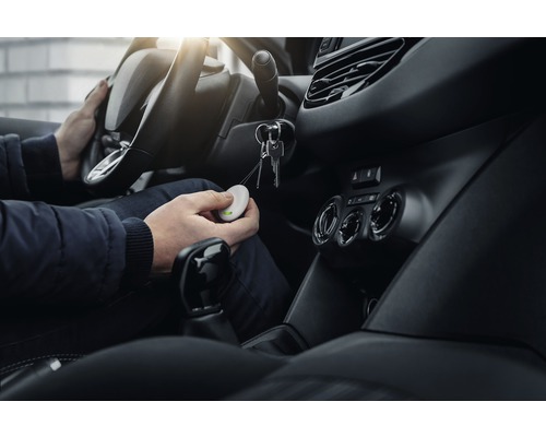 Persoon in auto houdt sleutelvinder in de hand