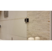 Detailopname van een badkamer met een betegelde muur en sanitair