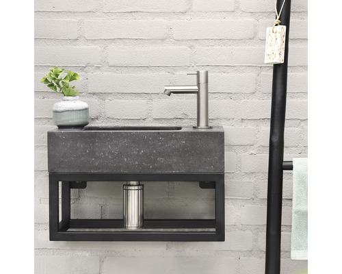 Moderne badkamer wastafel met kraan en handdoekhouder tegen een witte bakstenen muur