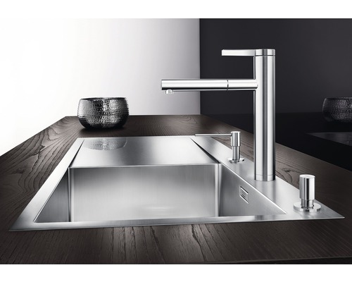 Roestvrijstalen spoelbak met kraan en zeepdispenser op een donker aanrechtblad