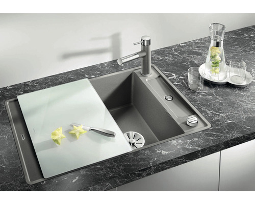 Spoelbak met snijplank en kraan op een donker aanrechtblad